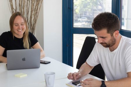 Zwei Personen schauen auf Laptop und Smartphone